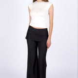 Woman wearing a white sleeveless top and black wide-leg pants on a white background