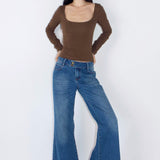 Woman wearing a brown top and blue jeans on a white background