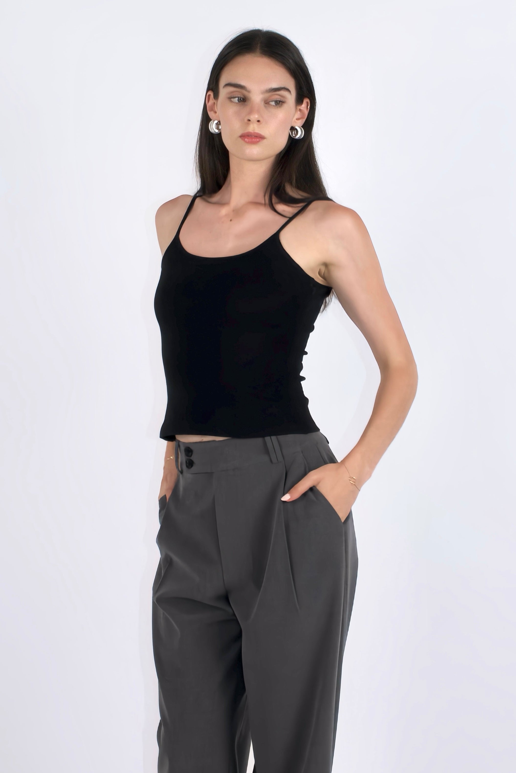 Woman wearing a black tank top and gray pants on a white background