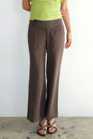 Woman wearing a green top and brown pants against a white background