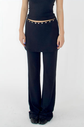 Person wearing a black outfit with pearl embellishments on a white background