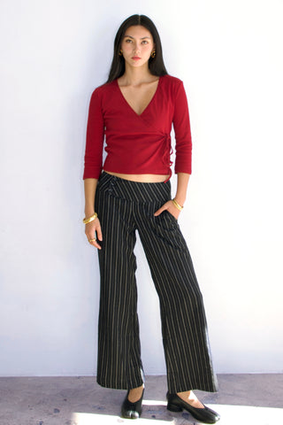 Woman wearing a red top and black pinstripe pants against a white background