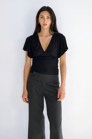 Woman wearing a black top and gray pants on a white background