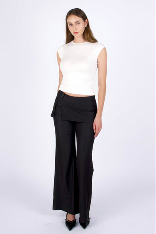 Woman wearing a white sleeveless top and black wide-leg pants on a white background