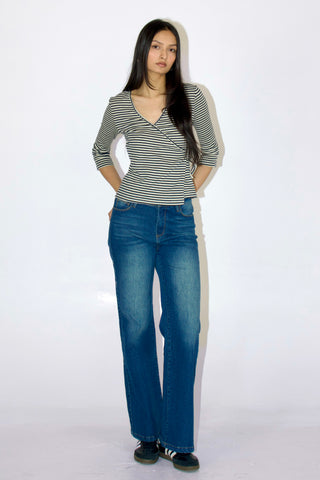 Woman wearing a striped shirt and blue jeans on a white background