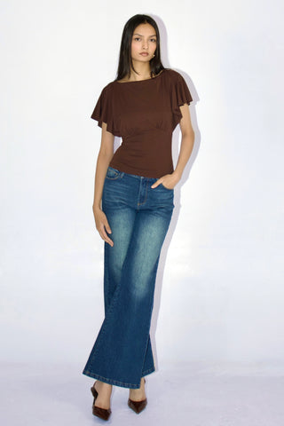 Woman wearing a brown top and blue jeans on a white background