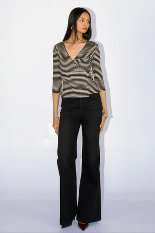 Woman wearing a striped top and black flared pants on a white background