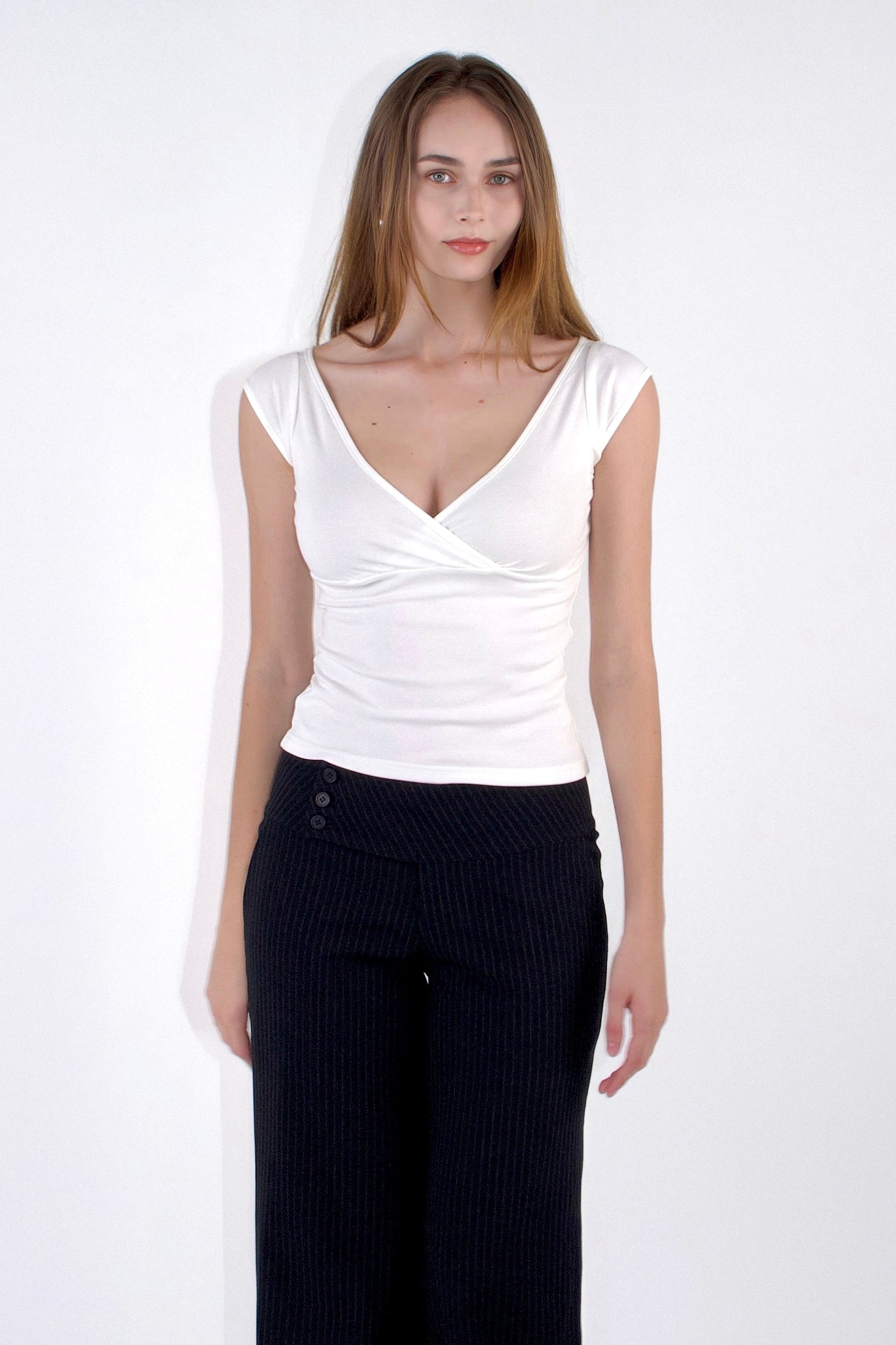 Woman wearing a white top and black pants on a white background