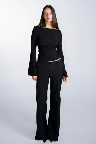 Woman wearing a black long-sleeve top and black pants on a white background