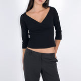 Woman wearing a black long-sleeve top and black pants against a white background