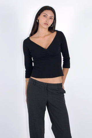 Woman wearing a black long-sleeve top and black pants against a white background