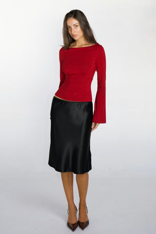 Woman wearing a red top and black skirt on a white background