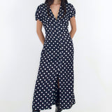 Woman wearing a black dress with white polka dots on a white background