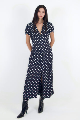 Woman wearing a black dress with white polka dots on a white background