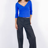 Woman wearing a blue top and black pants on a white background
