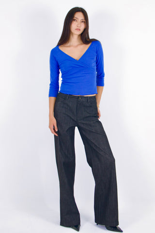 Woman wearing a blue top and black pants on a white background