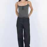 Woman wearing a gray tank top and dark pants on a white background