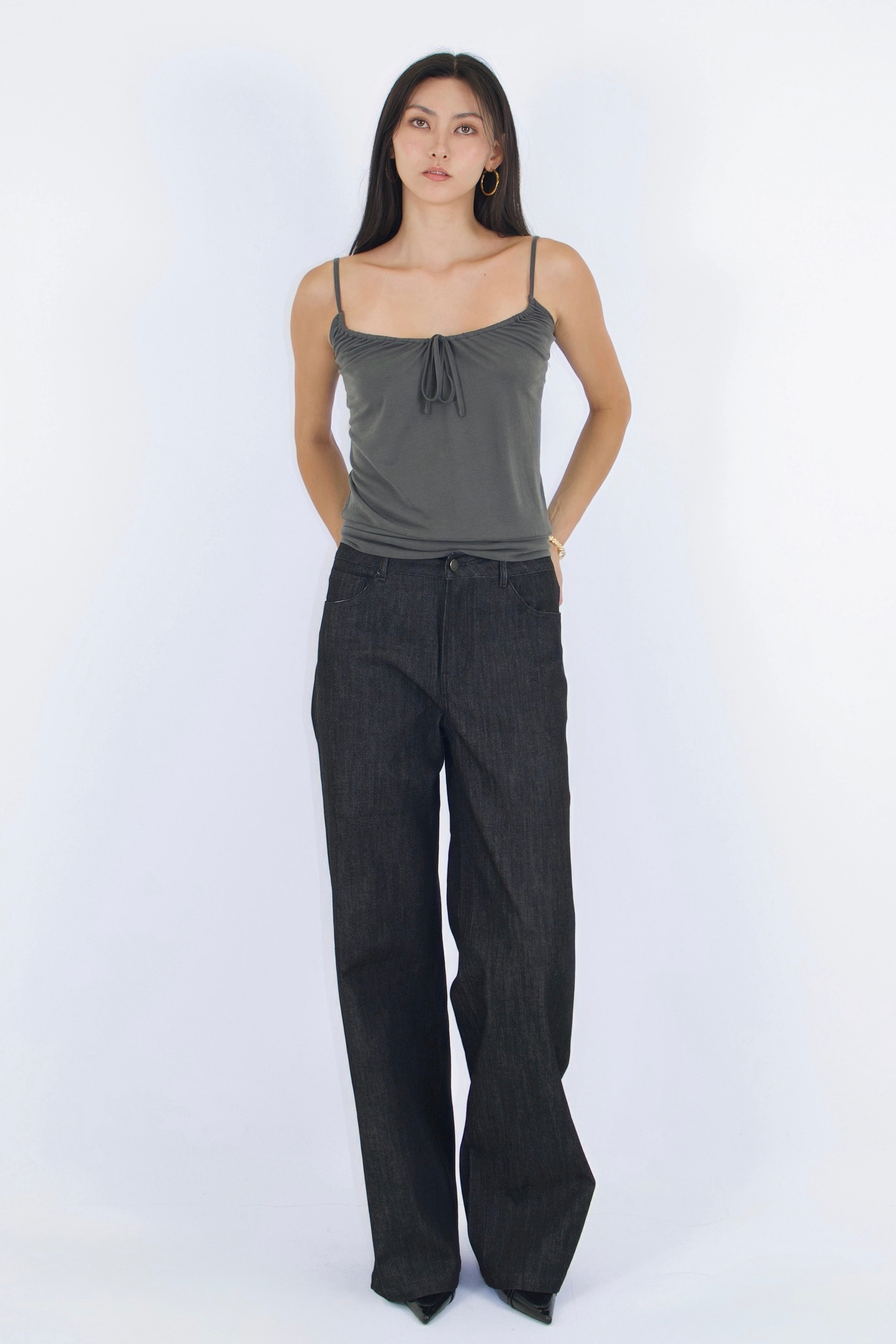 Woman wearing a gray tank top and dark pants on a white background