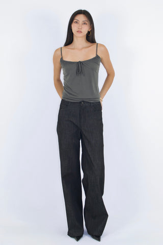 Woman wearing a gray tank top and dark pants on a white background