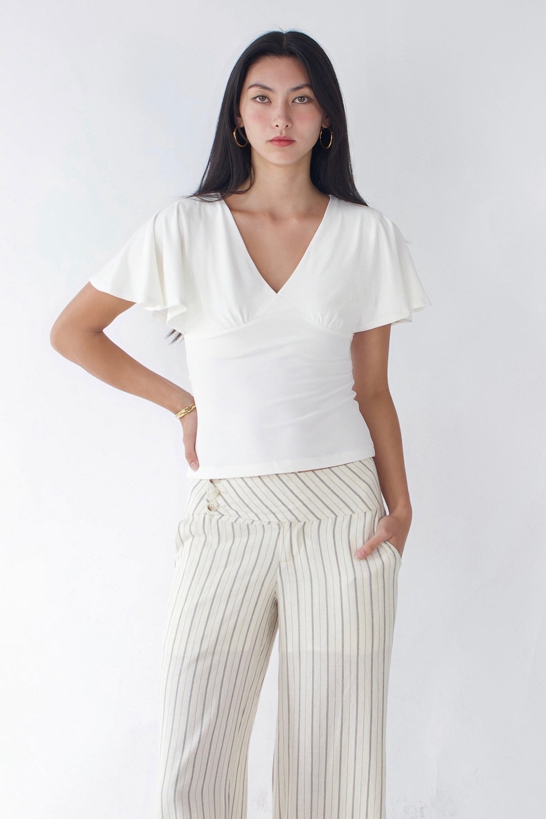 Woman wearing a white top and striped pants against a white background