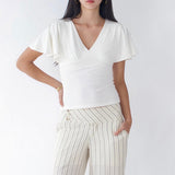 Woman wearing a white top and striped pants against a white background