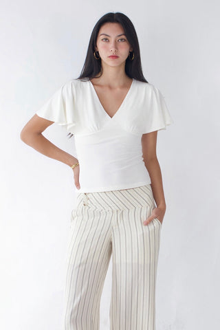 Woman wearing a white top and striped pants against a white background