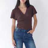 Woman wearing a brown top and blue jeans against a white background