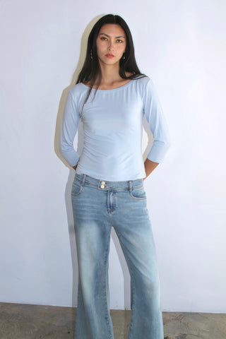 Person wearing a light blue top and jeans against a plain background