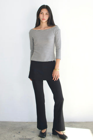 Woman wearing a striped shirt and black pants against a white background