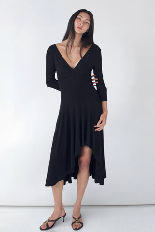 Woman wearing a black dress with cut-out sleeves against a white background